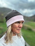 Head shot of woman standing outside wearing a grey and pink border beanie.