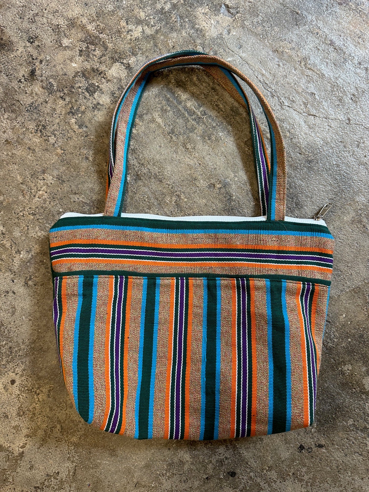 Striped fabric bag with colorful pattern on a concrete surface