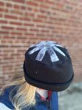 Black and white snowflake-patterned hat worn against a brick wall.