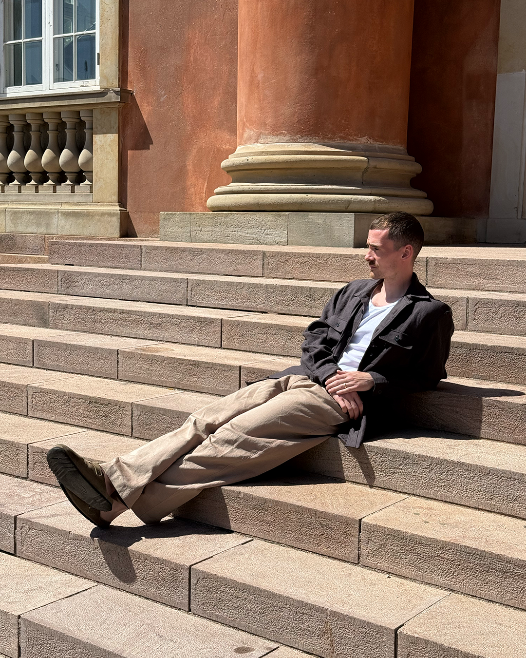 Man sitting on stone steps in front of a classical building