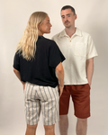 Two people standing side by side wearing casual clothing against a plain background