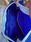Close-up of the inside of a blue bag with white trim being held open.